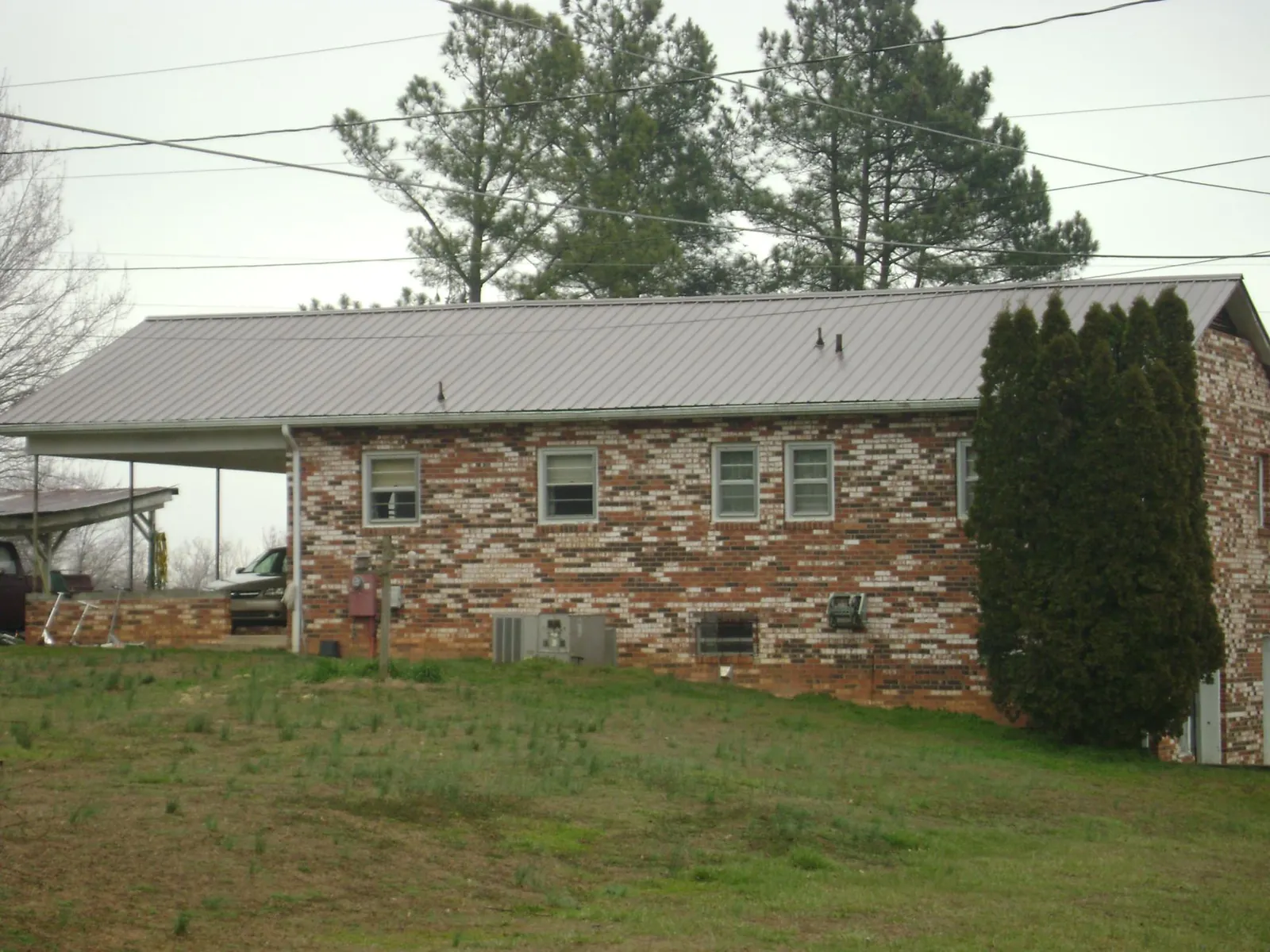 Gray metal roof on a brick split level home with a carport in Bedford